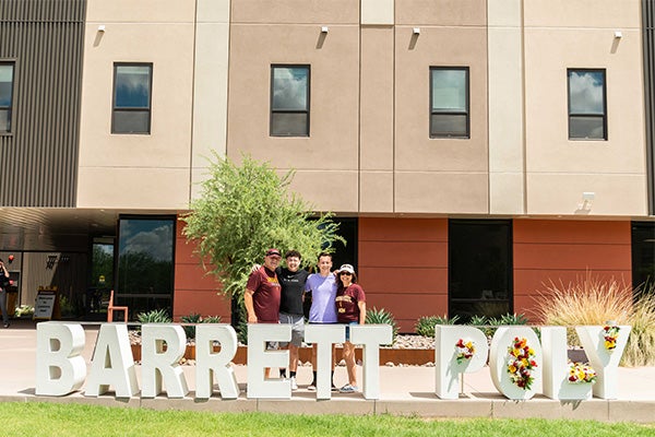 Barrett family standing outside the Barrett Poly sign in front of Lantana Hall at the Poly campus
