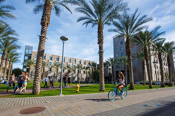 Students walking and biking outside the path in front of the Barrett Tempe complex at the Tempe campus
