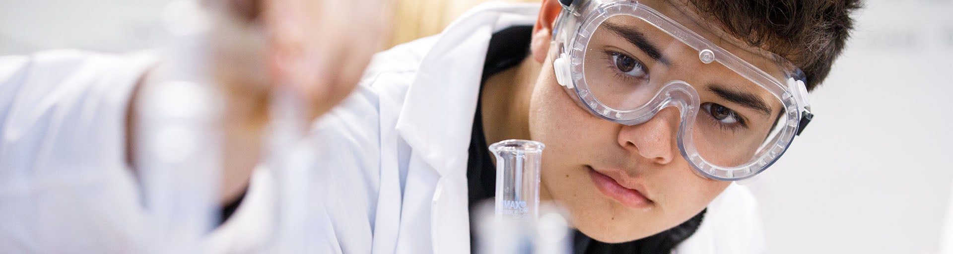 Close-up of student wearing a lab coat, working in a lab