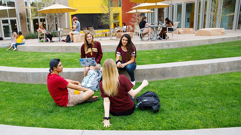 Four Barrett students sitting outside on the lawn of the great court at Barrett Tempe campus