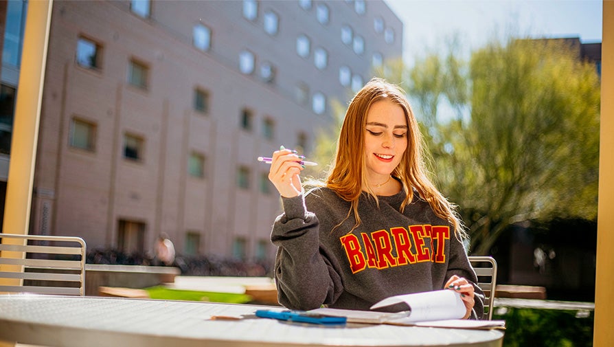 Barrett student studying outside the dorms on a patio table
