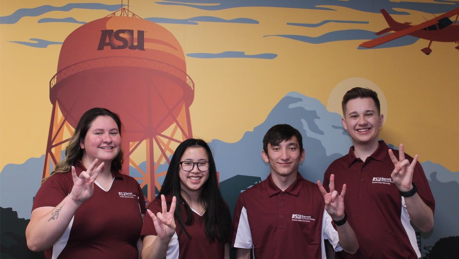 Four Barrett students wearing maroon in front of ASU Poly water tower artwork