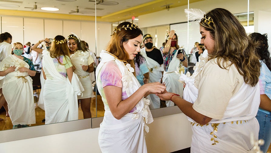 Two students helping each put on costumes