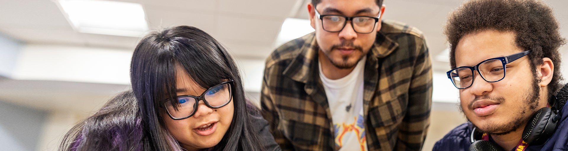 Three students engaged in a conversation inside the classroom