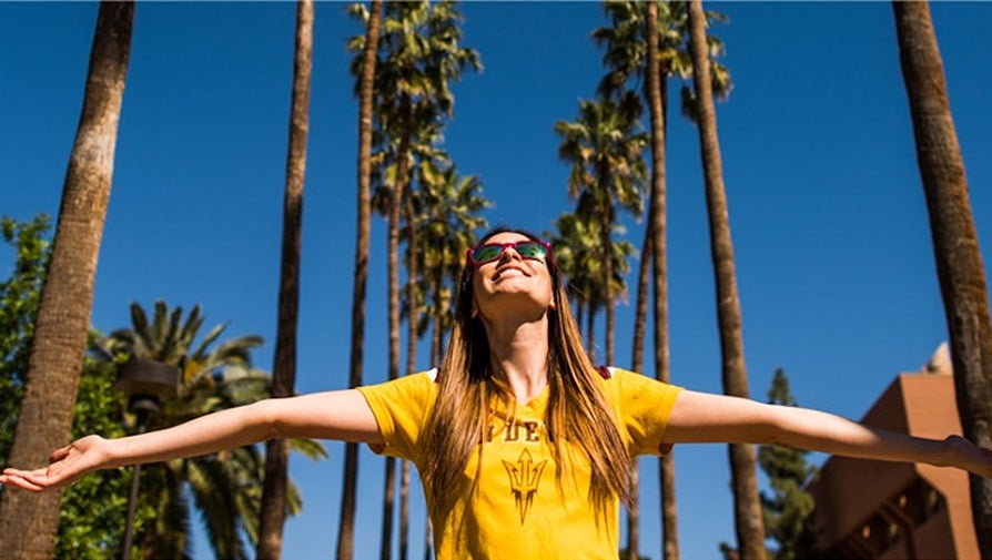 ASU student in gold t-shirt looking up to the sky