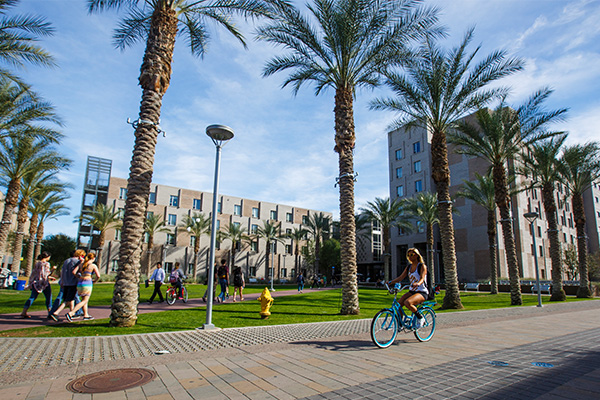 Students walking and biking outside the path in front of the Barrett Tempe complex at the Tempe campus