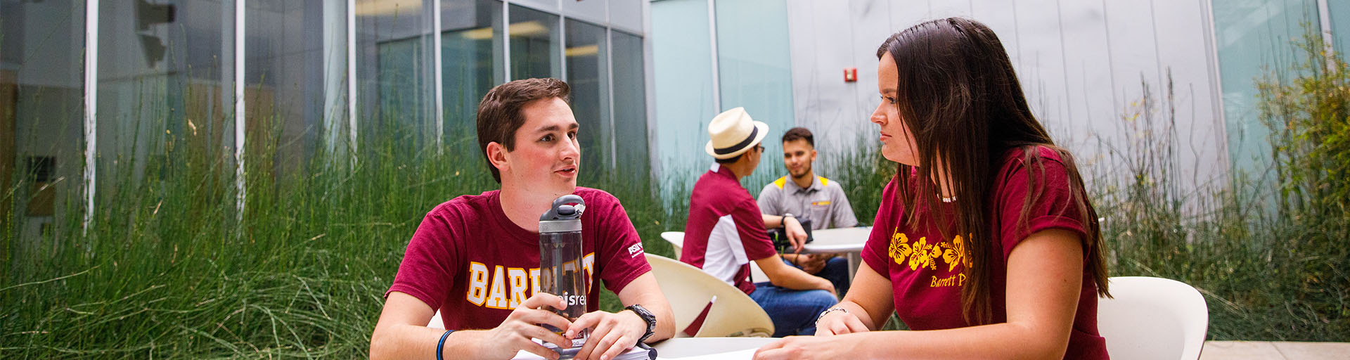 Male and female student having a conversation outside at a table